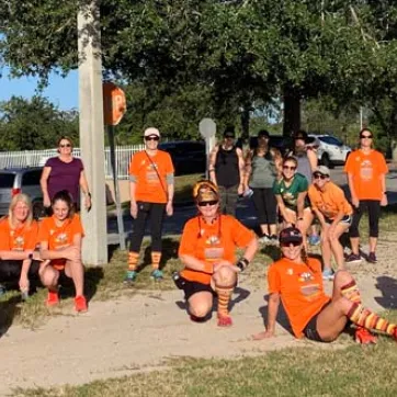 Group of runners wearing matching orange shirts outdoors 